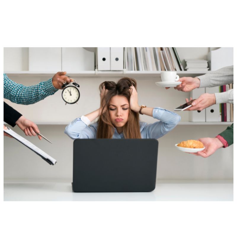 Person at desk with laptop and multiple demands symbolizing burnout