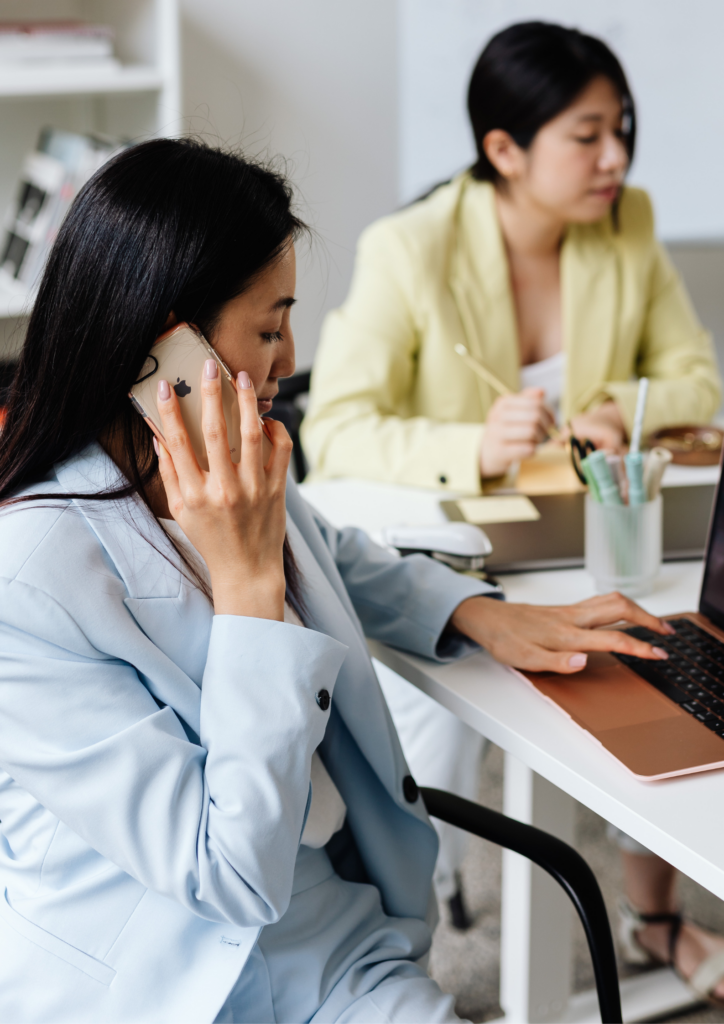 optimizing business processes, a woman on the cellphone on a call while using a laptop