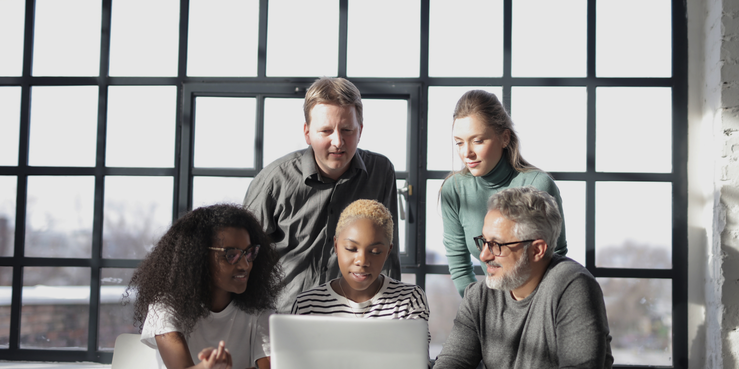 People Sitting at Table Near Window Using Laptop