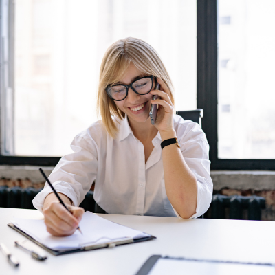 woman taking notes while in a phone call
